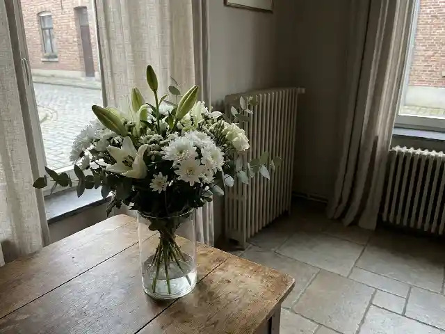 Bouquet de fleurs blanches dans un vase près d'une fenêtre